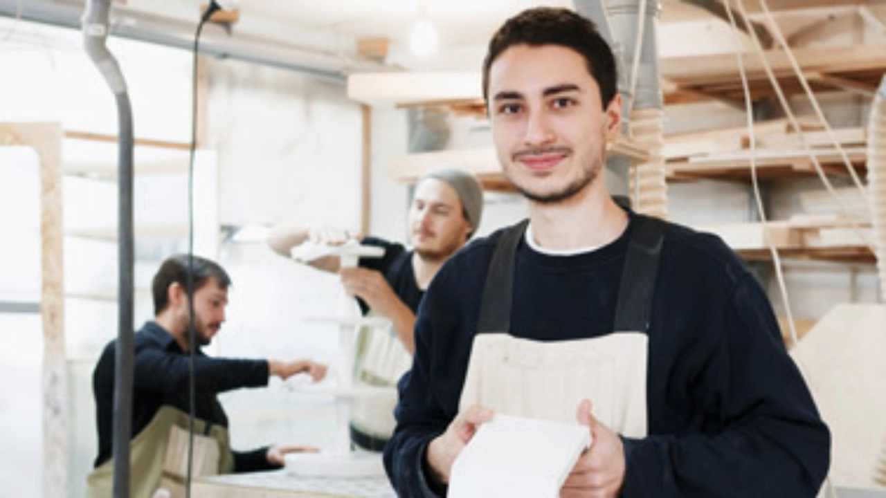 Junger Schreiner steht in einer Werkstatt.