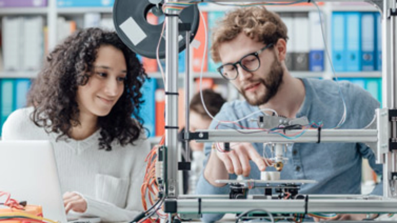 Zwei junge Ingenieure arbeiten an einem 3D-Drucker.