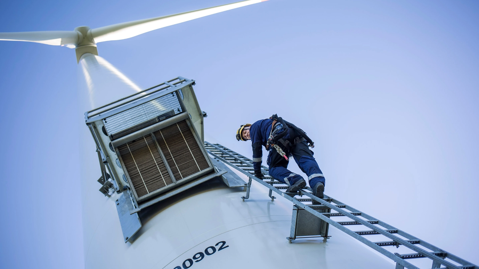 Ein Mann klettert auf ein Windrad.