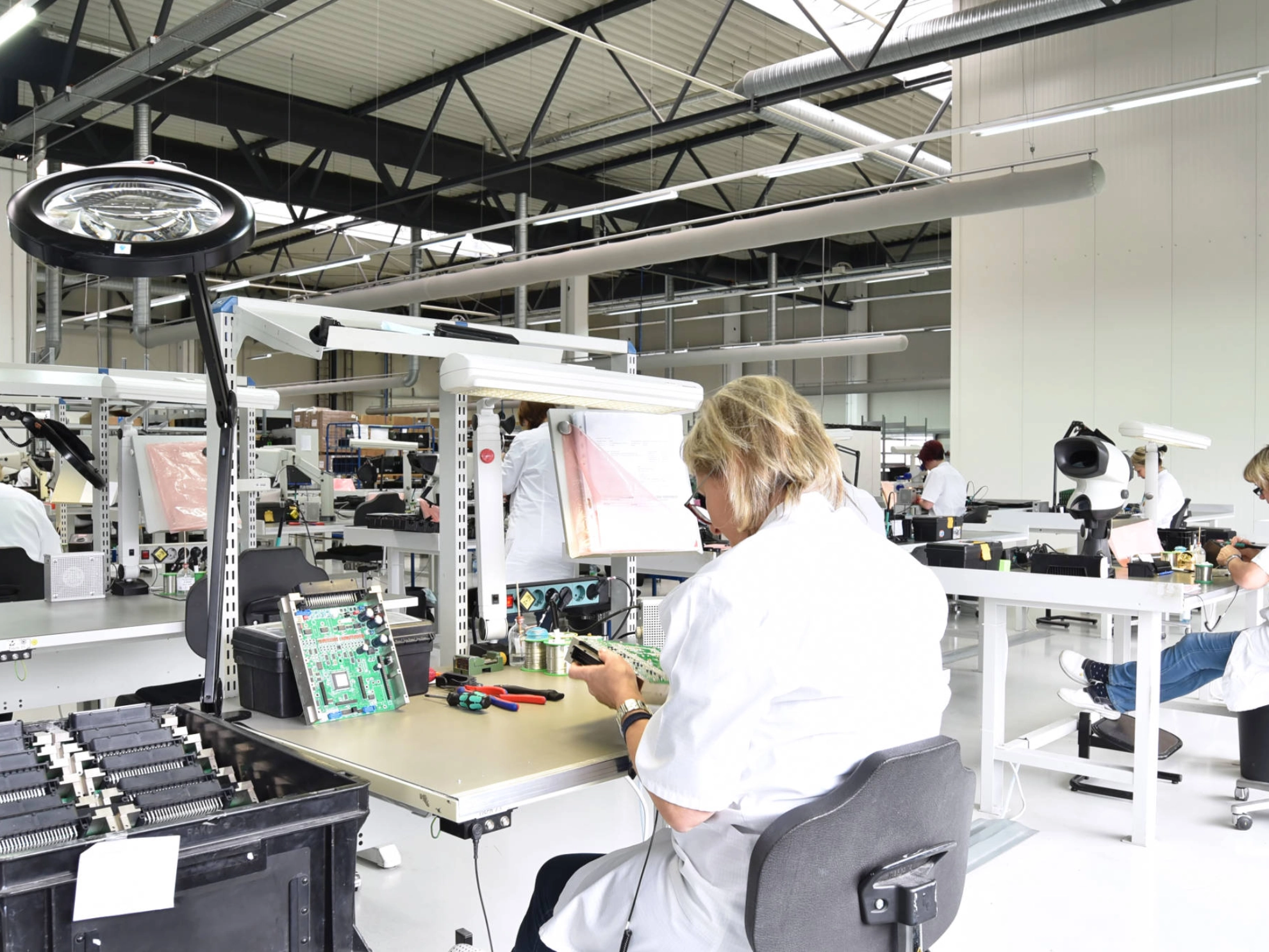 Frauen montieren Elektronik in einer Werkshalle.