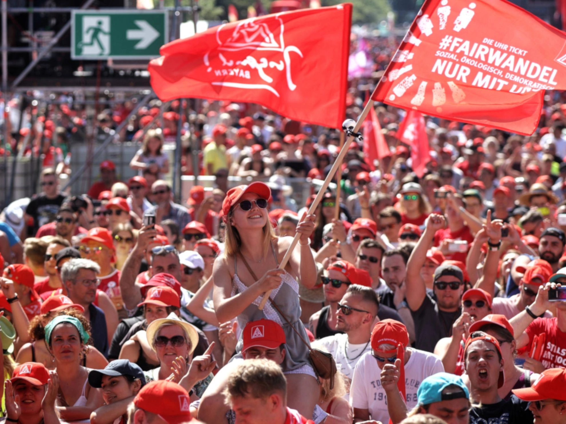 Eine junge Frau schwenkt eine Fahne auf der FairWandel-Kundgebung der IG Metall in Berlin.