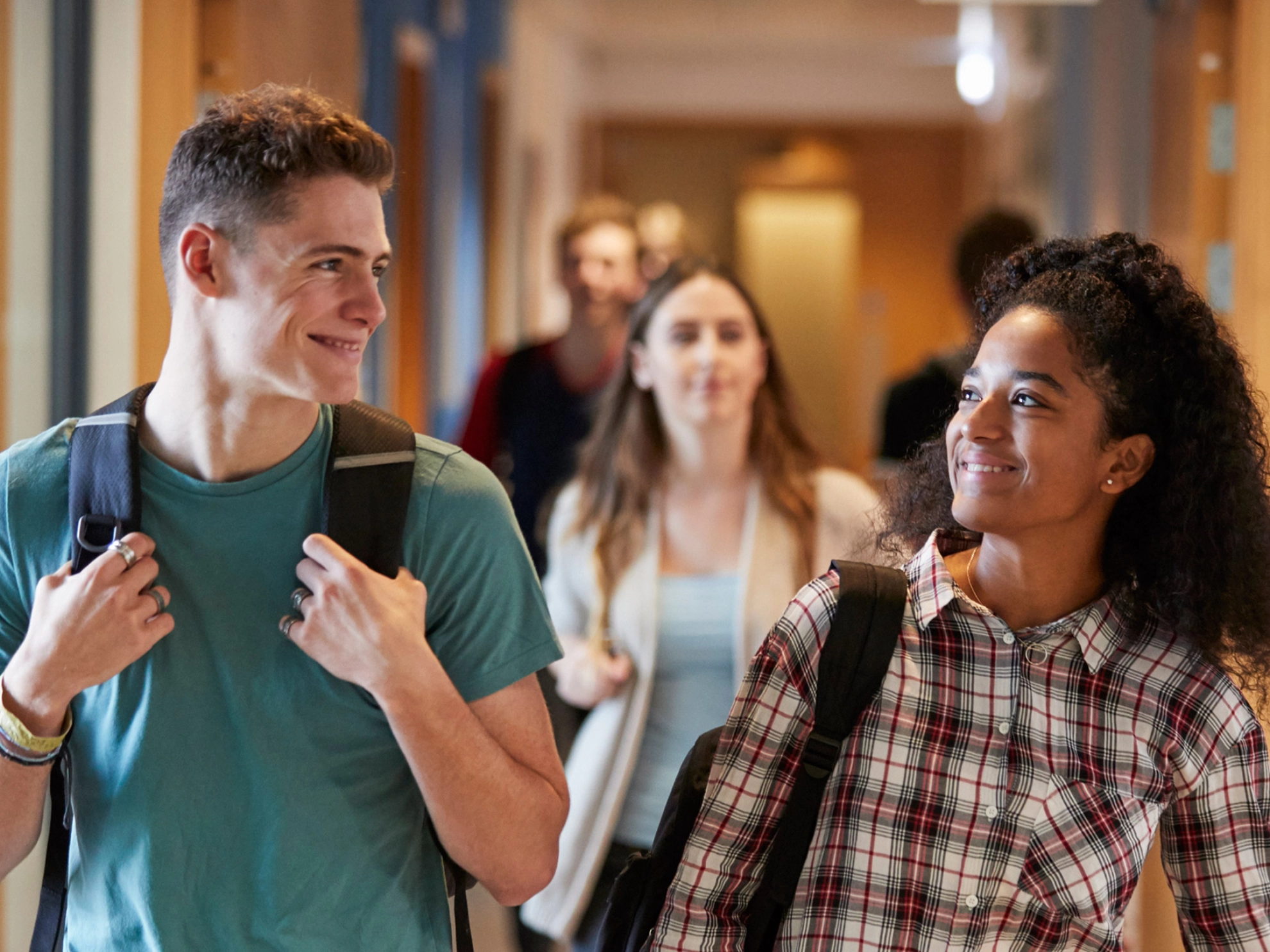 Eine Studentin und ein Student gehen gemeinsam über einen Korridor in einem Universitätsgebäude.