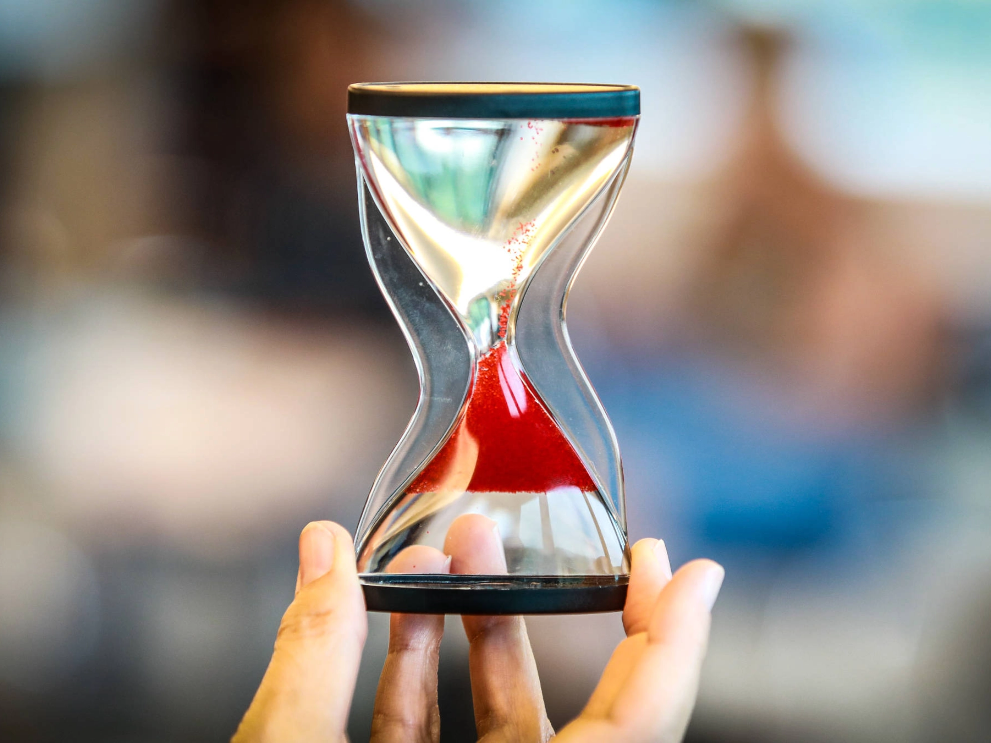 Eine Sanduhr, durch die roter Sand rinnt.