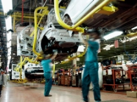 Zwei Männer arbeiten an Karosserien in einer Autofabrik.